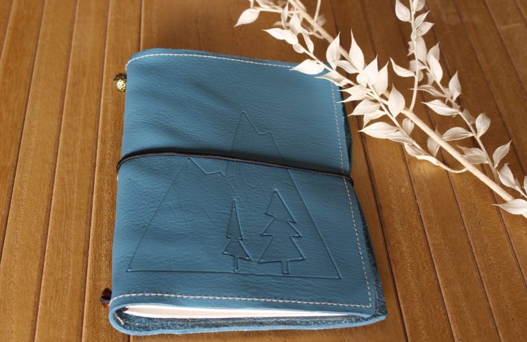 carnet de randonnée cuir Carnet de randonnée en cuir bleu orné de sapins gaufrés, fermé par un élastique noir