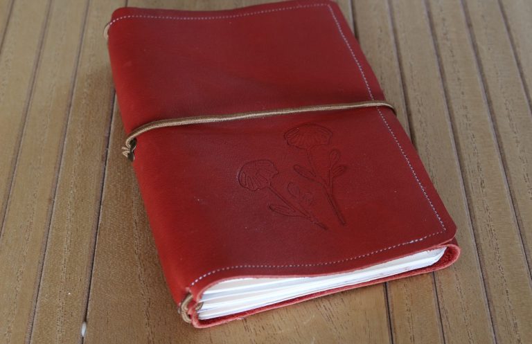 Carnet rechargeable en cuir rouge Carnet rechargeable en cuir rouge fermé par un élastique, avec ses cahiers visibles